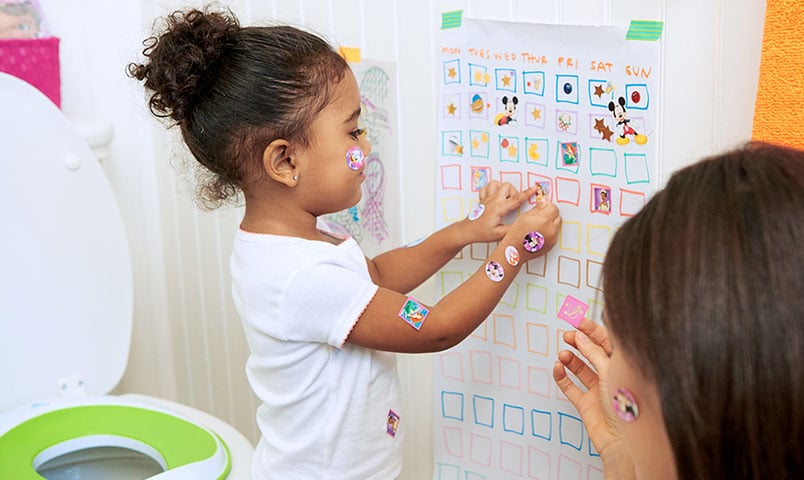 Girl adding stickers to Potty Chart