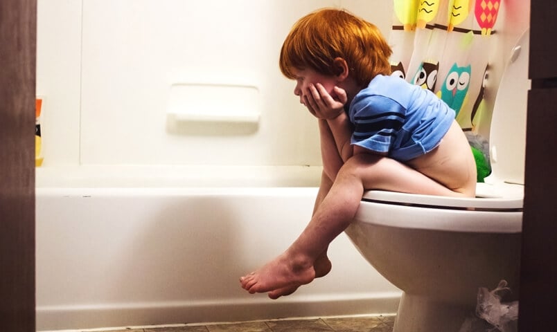 Enfant constipé assis sur la toilette dans la salle de bain