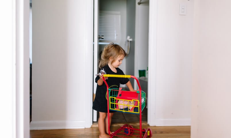 Child with a small shopping cart in the middle of a hallway