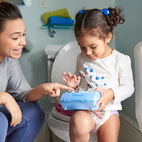 Petite fille assise sur l'apprentissage de la propreté des toilettes avec un parent