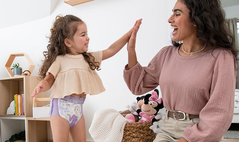 Mom and toddler potty training with Pull-Ups®, high-fiving success.